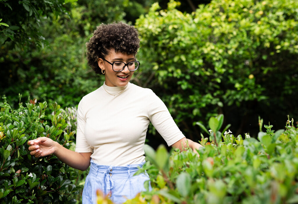 Woman examining plants and shrubs in a landscaped garden